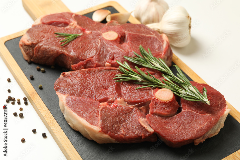 Board with steak meat, herbs and spices on white background