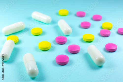Colored pills and tablets on green background. Close up. Medical treatment concept.