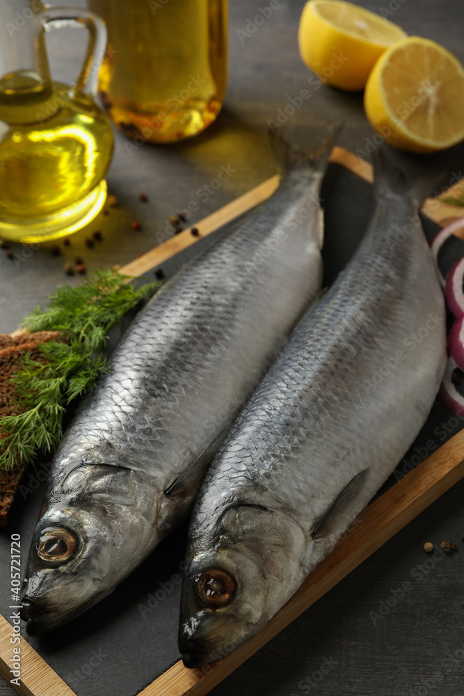 Obraz premium Board with herring fish and spices, and oil on dark wooden background