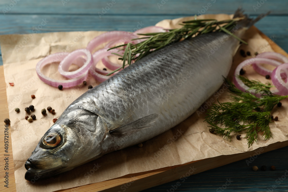 Board with fresh herring fish and spices on wooden background Board with fresh herring fish and spices on wooden background