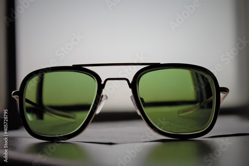 Glasses for eyesight in beautiful sunglass frame with green color glass in it put on a wooden table and fogg weather behind it