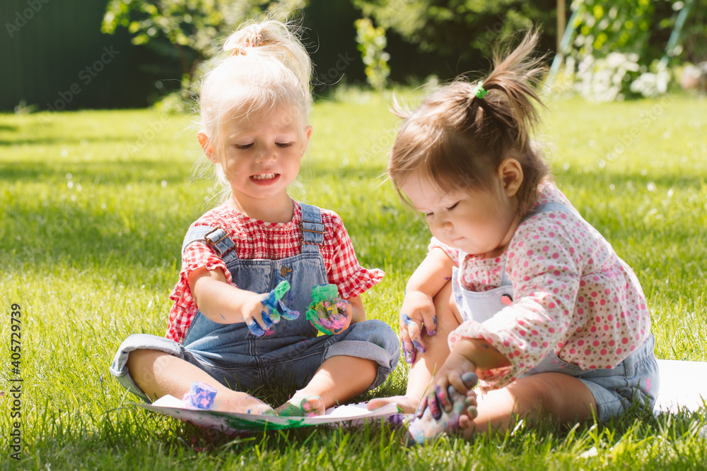 Two little girls sisters paint with finger paints Two little girls sisters paint with finger paints