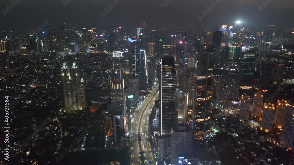 Descending aerial pedestal shot of night time highway traffic through busy modern city center in Jakarta Descending aerial pedestal shot of night time highway traffic through busy modern city center in Jakarta