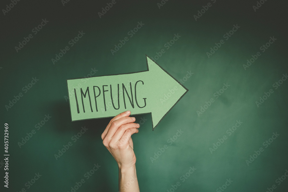Hände halten einen grünen Pfeil auf dem das Wort Impfung geschrieben steht. Hände halten einen grünen Pfeil auf dem das Wort Impfung geschrieben steht.