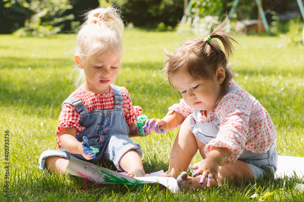 Two little girls sisters paint with finger paints Two little girls sisters paint with finger paints