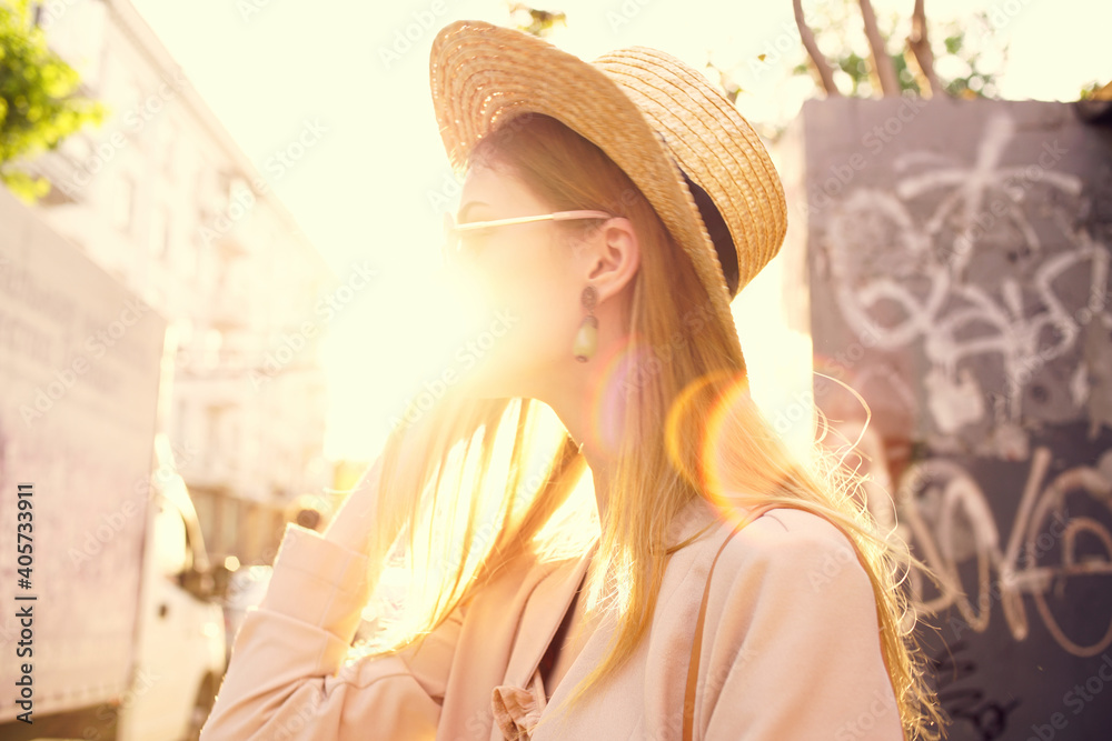 Cheerful woman in a hat and sunglasses walking through the city outdoors in the sun