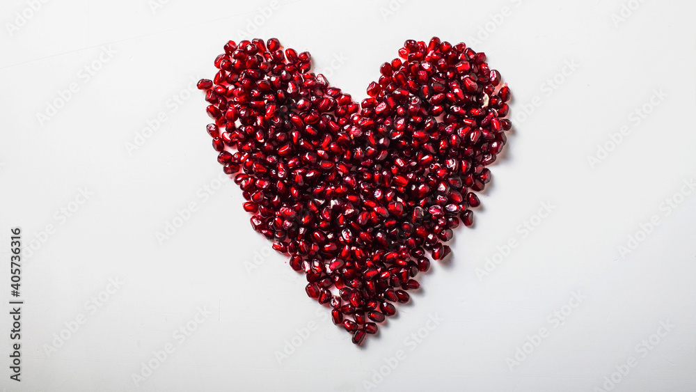 Heart shape pomegranate seeds on white background.  Valentines helthy love concept.