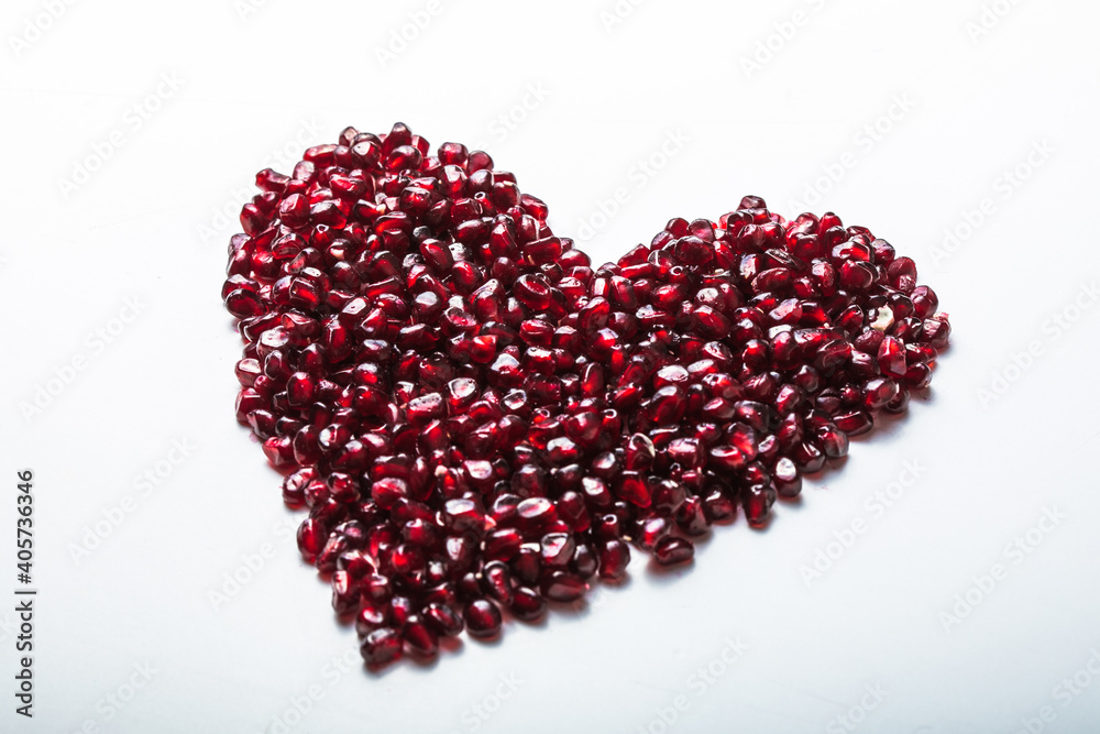 Heart shape pomegranate seeds on white background. Valentines helthy love concept. Heart shape pomegranate seeds on white background. Valentines helthy love concept.