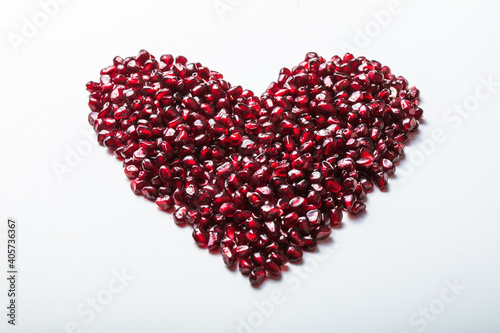 Heart shape pomegranate seeds on white background.  Valentines helthy love concept.