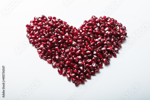 Heart shape pomegranate seeds on white background. Valentines helthy love concept.