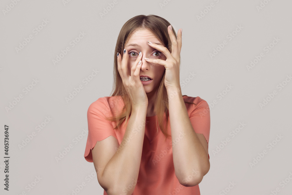 Worried and concerned blond girl is looking with frightened expression. Studio shot, gray background Worried and concerned blond girl is looking with frightened expression. Studio shot, gray background