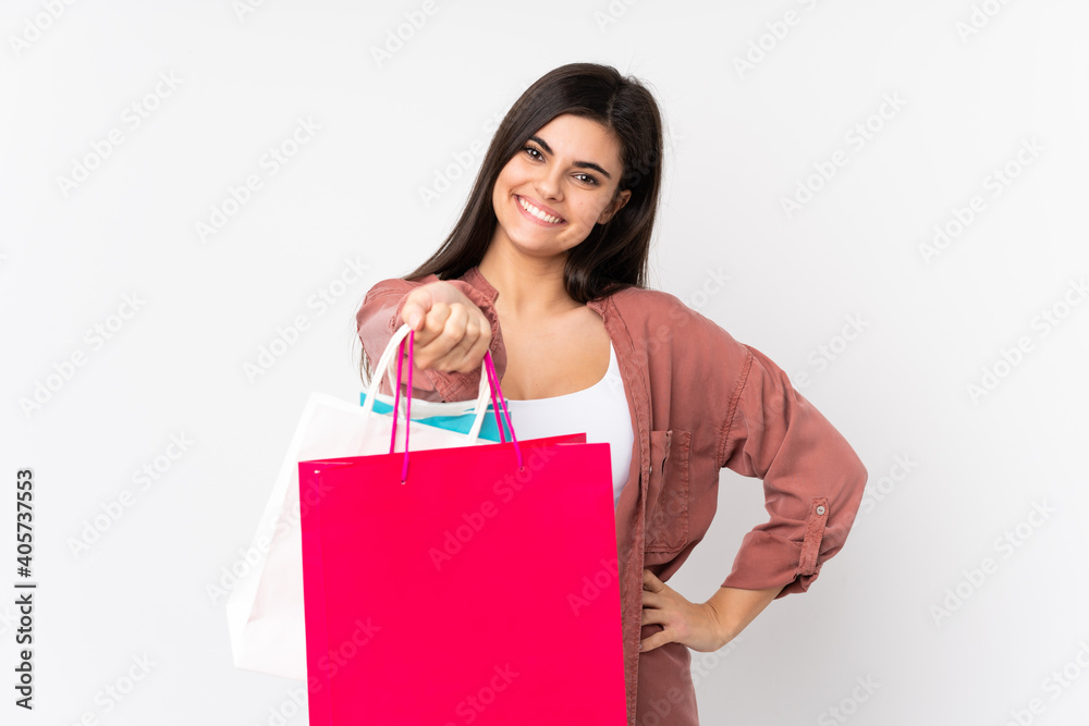 Young woman over isolated white background holding shopping bags and giving them to someone Young woman over isolated white background holding shopping bags and giving them to someone