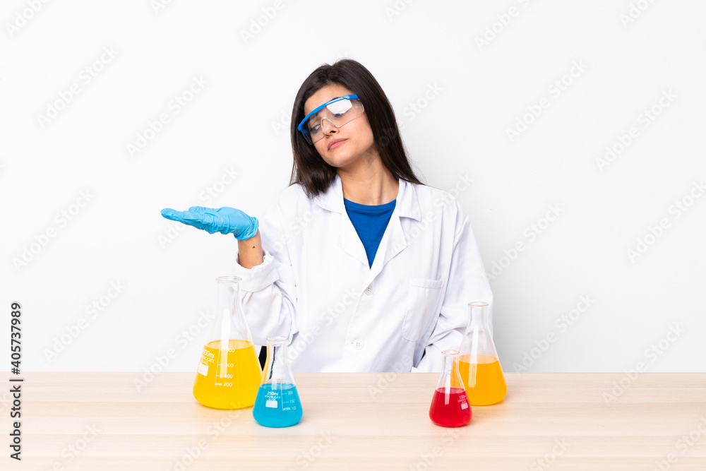 Young scientific woman in a table holding copyspace with doubts Young scientific woman in a table holding copyspace with doubts