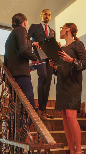 Businesswomen meeting on stairs in finance corporate company analyse graphs standing on stairscase. Group of professional successful businesspeople working in modern financial building