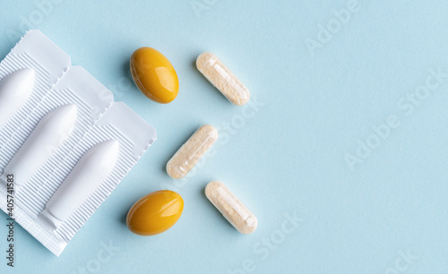 Vaginal suppositories on blue background. Top view. Copy space. Vulvovaginal infections treatment. Gynecological medicines for womens health in form of suppository, capsules and oval shaped pill. 