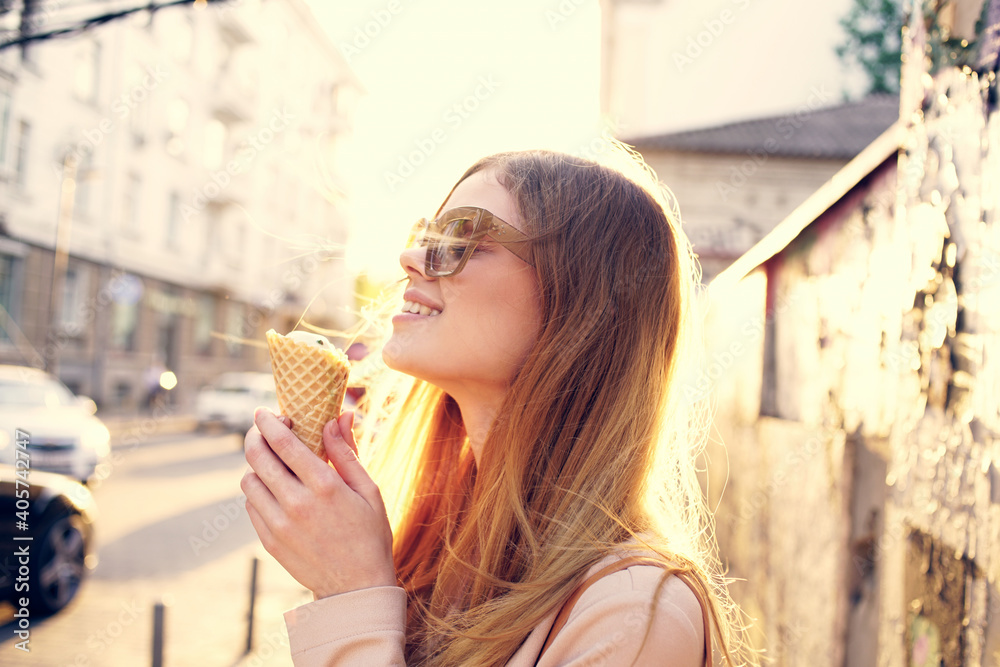 Cheerful woman in sunglasses in the city on the street walk with ice cream Cheerful woman in sunglasses in the city on the street walk with ice cream