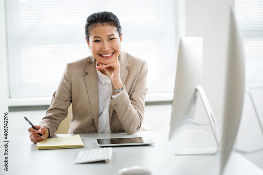 Asian business woman smiling at camera in an office Asian business woman smiling at camera in an office