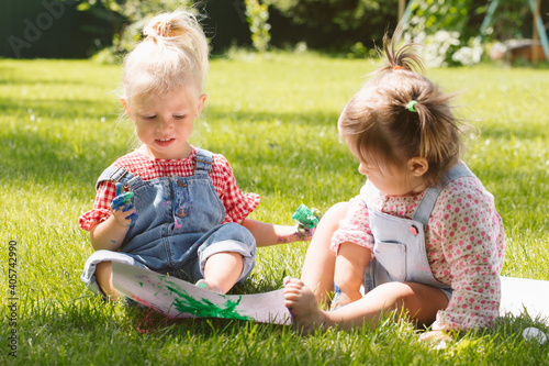 Two little girls sisters paint with finger paints