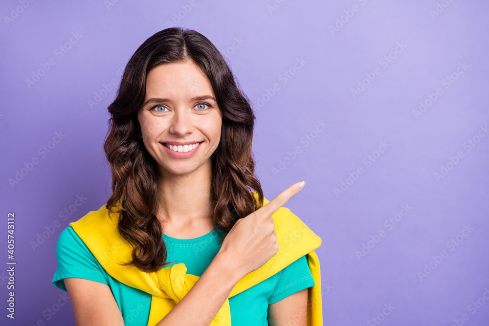 Photo of charming curly young lady wear sweater shoulders smiling pointing empty space isolated violet color background Photo of charming curly young lady wear sweater shoulders smiling pointing empty space isolated violet color background