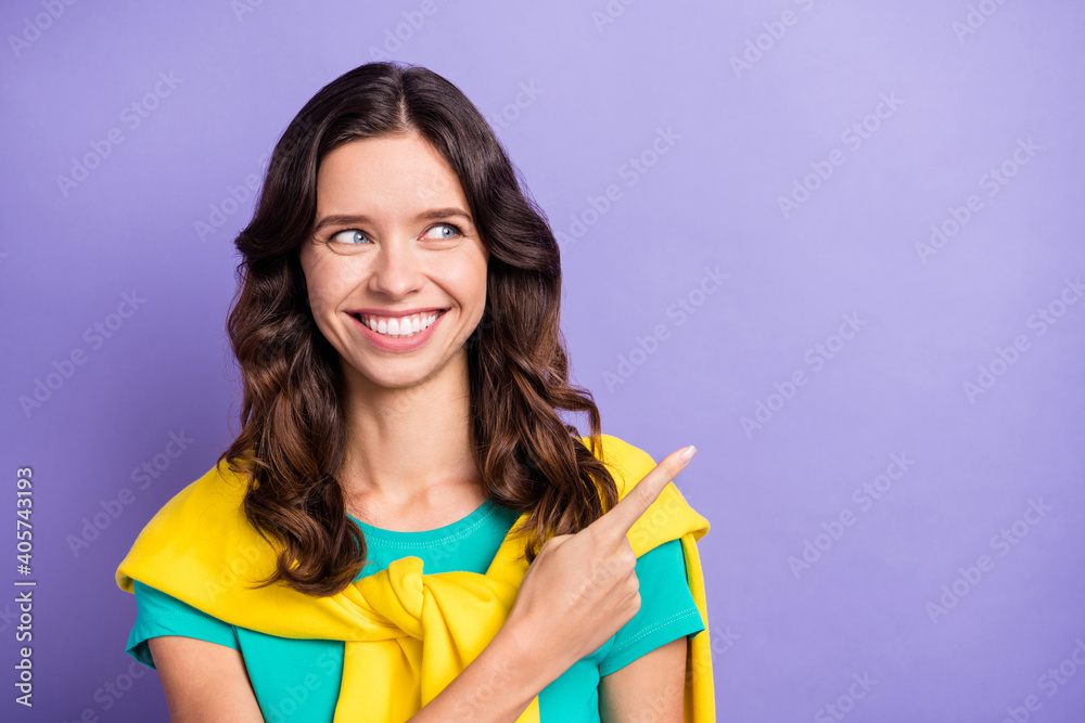 Photo of sweet wavy young woman dressed pullover shoulders looking pointing empty space isolated purple color background Photo of sweet wavy young woman dressed pullover shoulders looking pointing empty space isolated purple color background