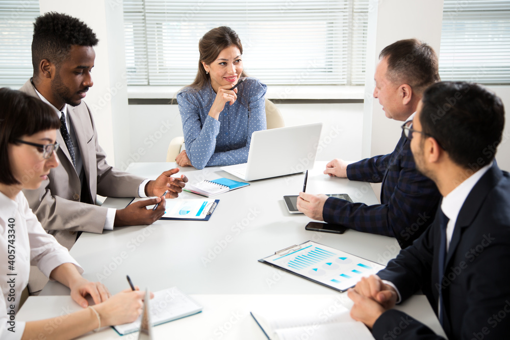 Group of business people sitting around the office desk and discussing the project Group of business people sitting around the office desk and discussing the project