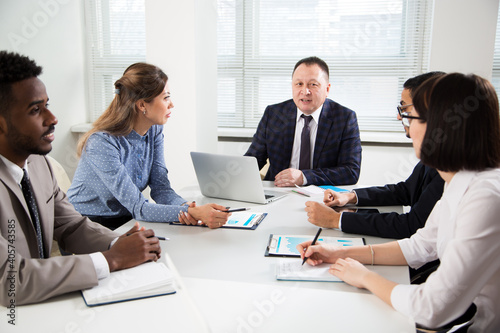 Group of business people sitting around the office desk and discussing the project