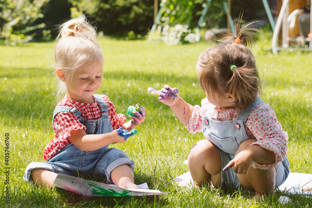 Two little girls sisters paint with finger paints Two little girls sisters paint with finger paints