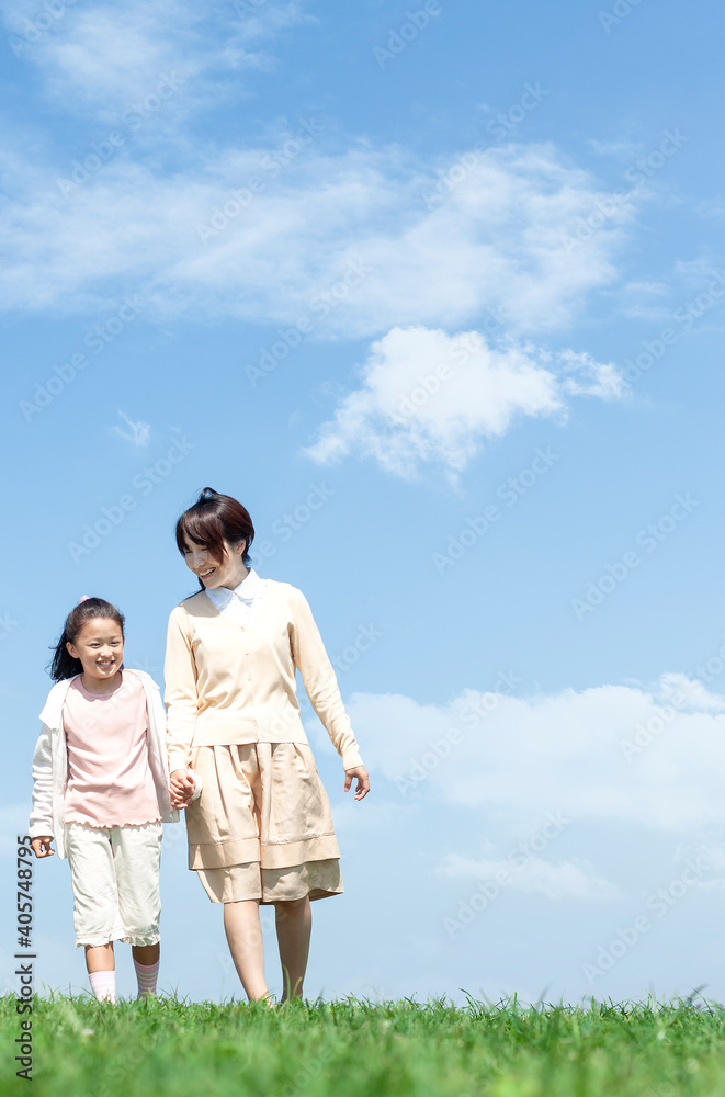 芝生を歩く母親と娘