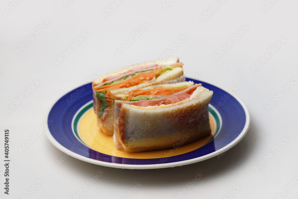 Sandwich with ham, egg, tomatoes, lettuce and toasted bread on a plate. High angle view isolated on white background. Sandwich with ham, egg, tomatoes, lettuce and toasted bread on a plate. High angle view isolated on white background.