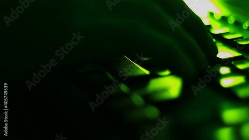 Typing on the laptop keyboard in the dark room, office. Close up, point to fingers.