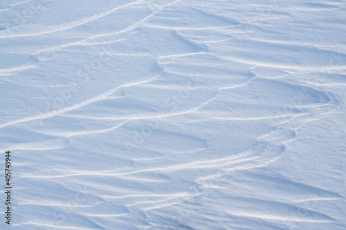 Beautiful winter background with snowy ground. Natural snow texture. Wind sculpted patterns on snow surface.
