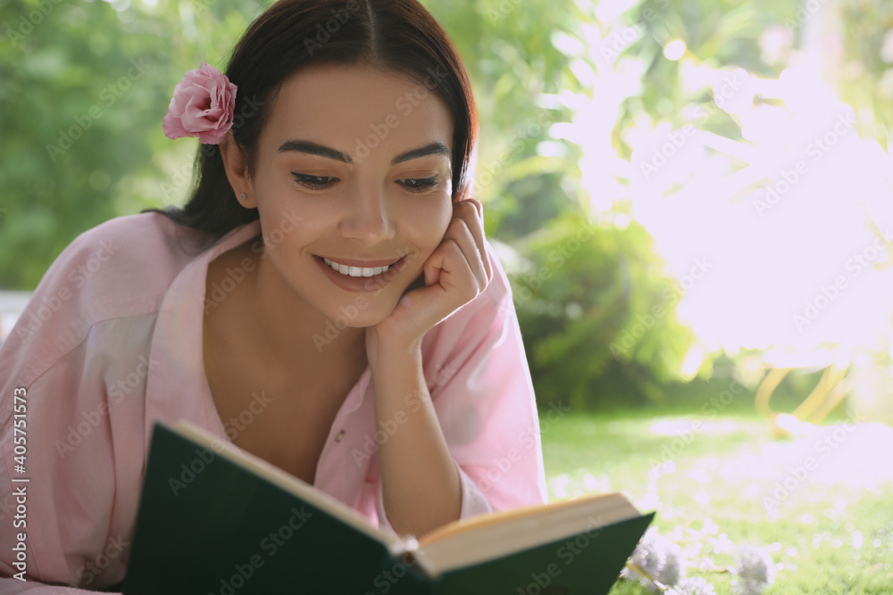 Fototapeta premium Beautiful young woman reading book in park on sunny day