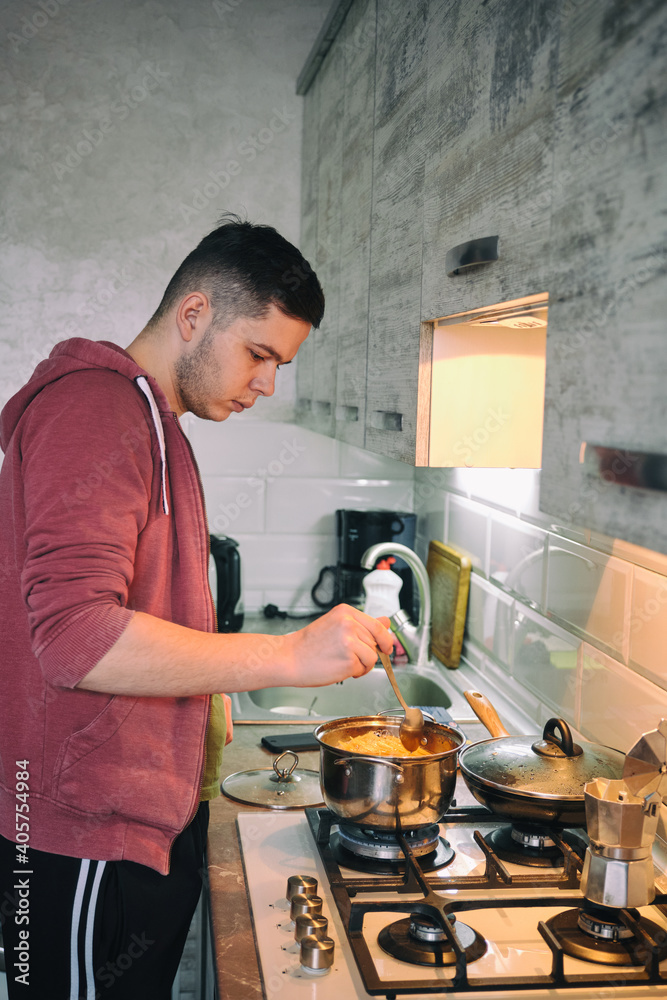Man cooking pasta spaghetti at home in the kitchen. Guy cooking a tasty meal. Man cooking pasta spaghetti at home in the kitchen. Guy cooking a tasty meal.