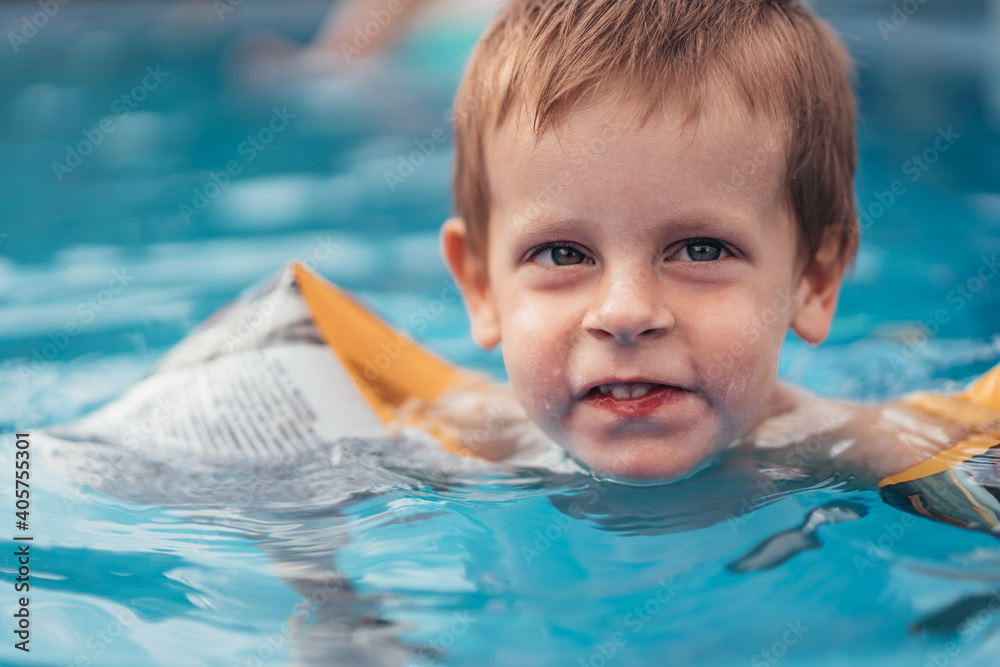 Foto de Baby boy swims independently in the pool. Little child boy learning how to swim in