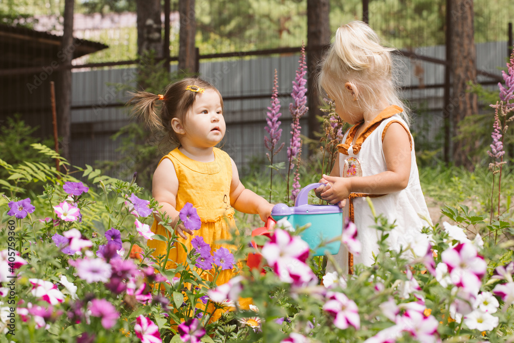 Two little girls sisters watering flowers Two little girls sisters watering flowers