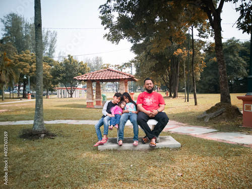 A happy family is sitting on the bench in the park.