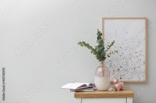 Vase with fresh eucalyptus branches on cabinet in room. Interior design