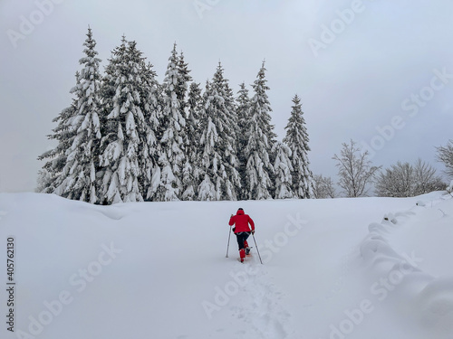 woman with red jacket climb on the snow with snowshoes
