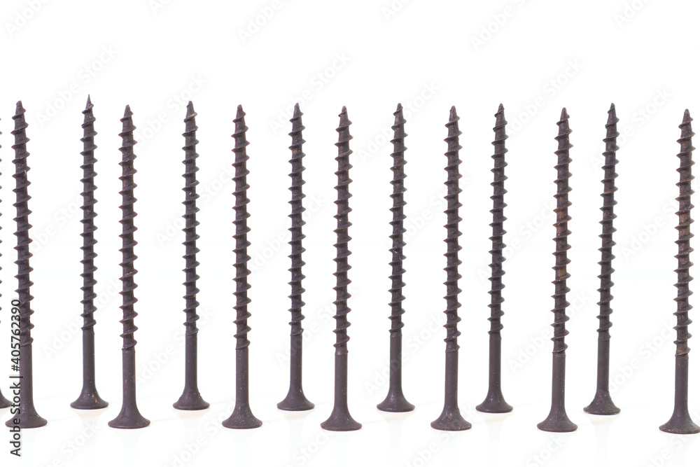 Self-tapping screws for wood surfaces, standing on hats, on a light background. Components for construction and repair. Metal fasteners. Self-tapping screws for wood surfaces, standing on hats, on a light background. Components for construction and repair. Metal fasteners.