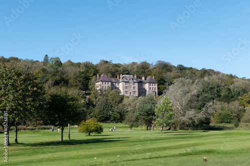 Large house behind trees next to golf course in Lake District