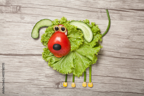 Funny vegetable dog made of salad, tomato, cucumber on wooden background. Fun food for kids. Cooking idea for children party.