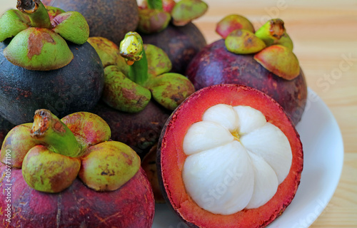 Closeup of Delectable Juicy White Flesh of Ripe Mangosteen Fruit with Blurry Whole Fruits on a Plate