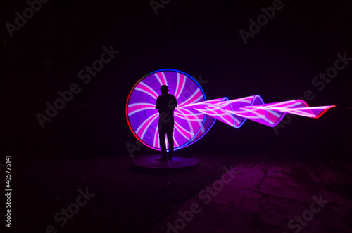 one person standing against beautiful red and purple circle light painting as the backdrop