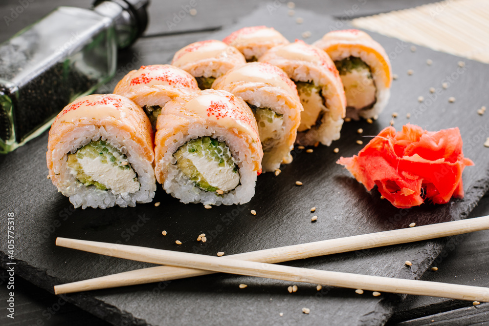 Tasty fresh sushi rolls with salmon on black background Tasty fresh sushi rolls with salmon on black background