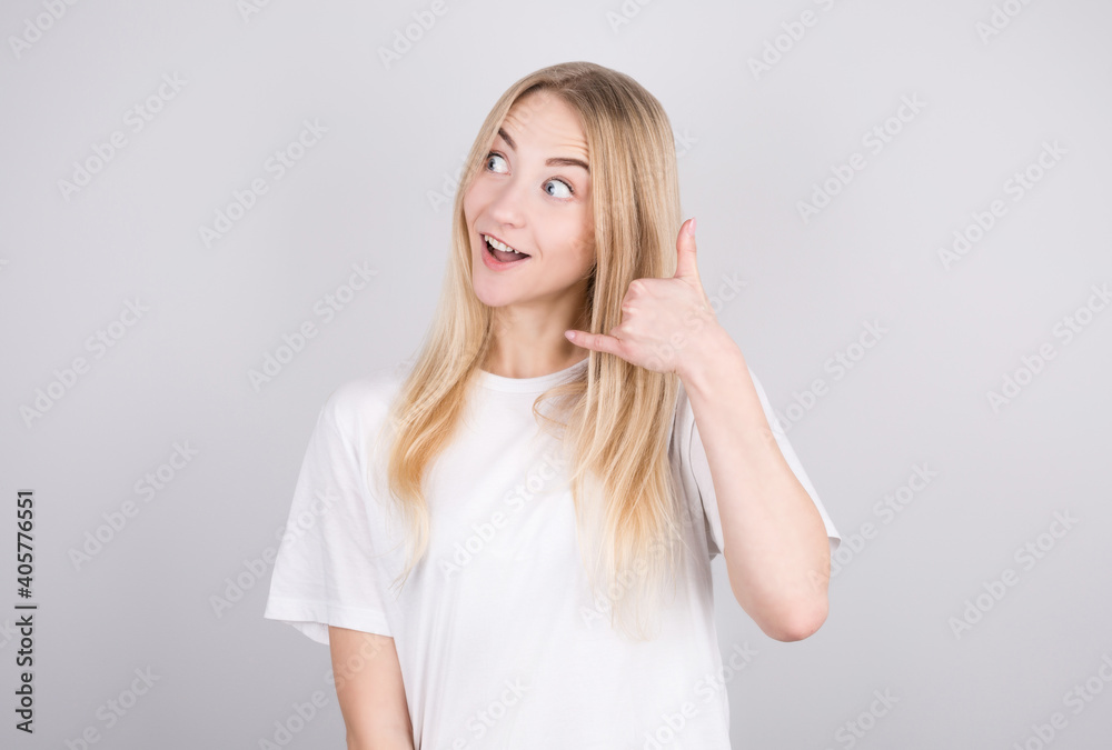 A young girl makes a surprised face, looks up, making a telephone gesture with her hand and fingers, as she talks on the phone. A young girl makes a surprised face, looks up, making a telephone gesture with her hand and fingers, as she talks on the phone.