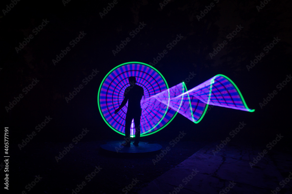 one person standing against beautiful purple and green circle light painting as the backdrop