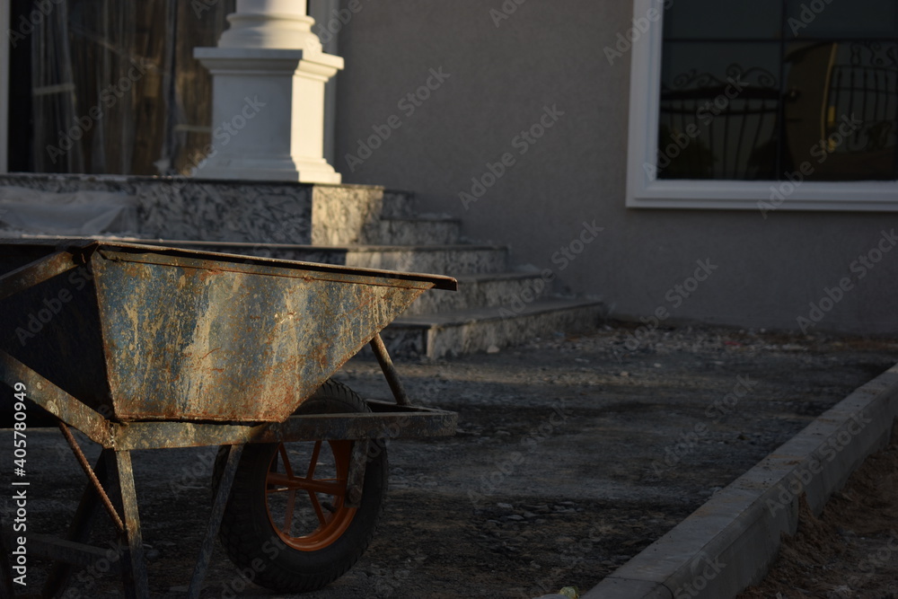 wheelbarrow in the construction area, villa construction in the background wheelbarrow in the construction area, villa construction in the background