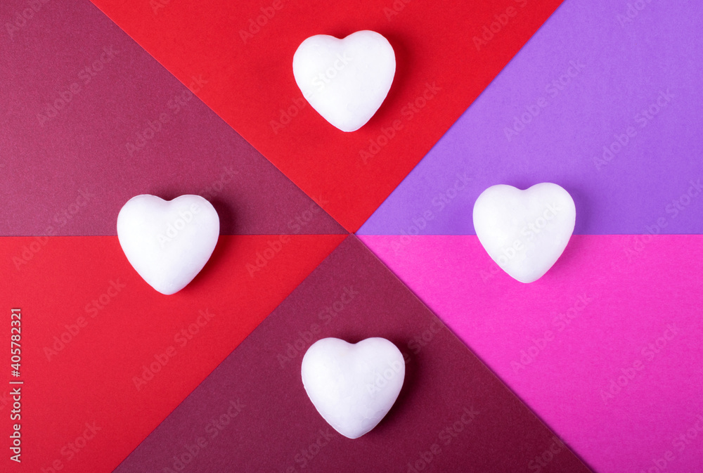 Obraz premium Geometric backdrop for Valentine's Day. White hearts against the pink, red and purple background. Flat lay