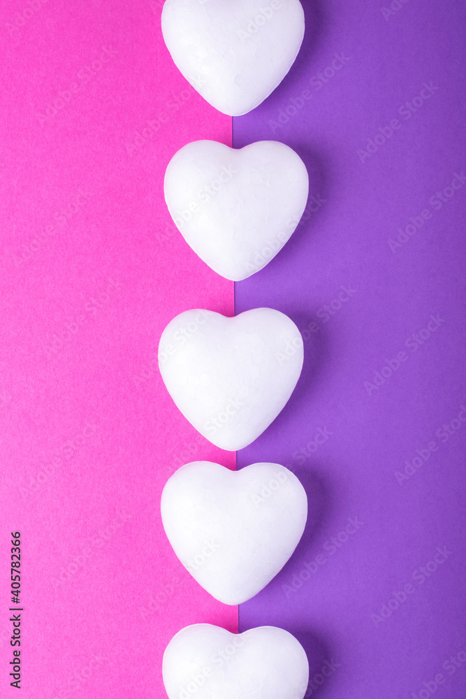 Line of white hearts on two colored pink and purple geometric background. Valentine's Day backdrop. Conceptual flat lay