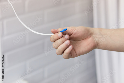 a man holds an insulated live wire. Blue electrical tape on the wire. High voltage. Electrician makes house wiring